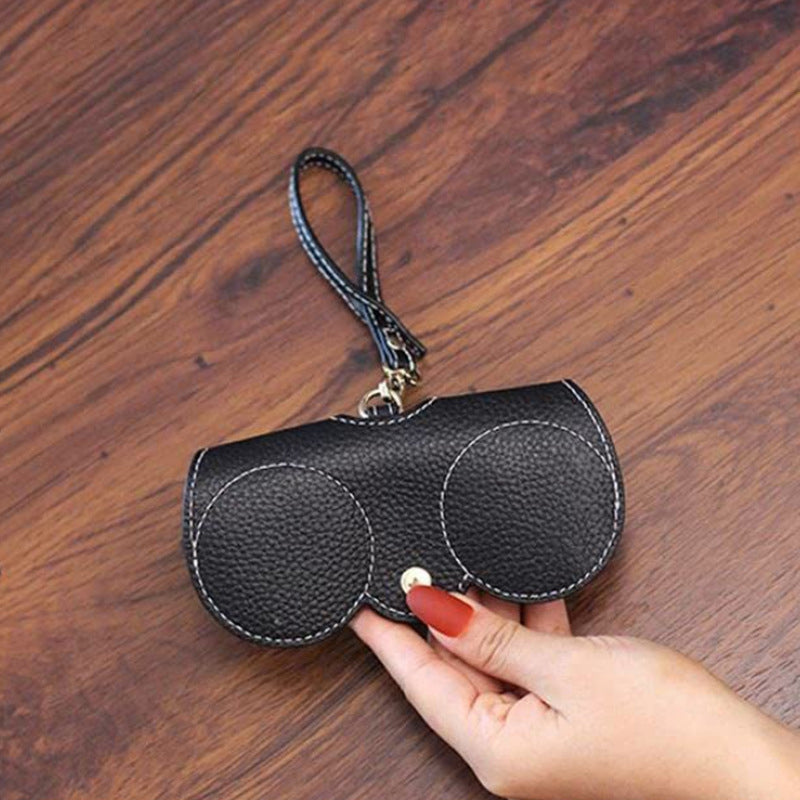 Stylish fashion sunglasses case in black leather with a sleek design and convenient wrist strap for easy carrying